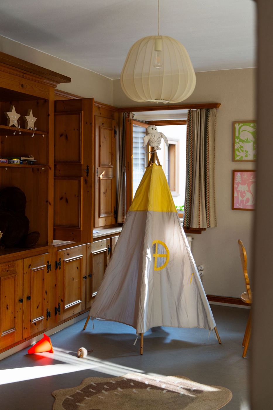 Das Spielzimmer mit einem Tipi-Zelt, Spielen im Holzschrank und gerahmten Bildern an der Wand.