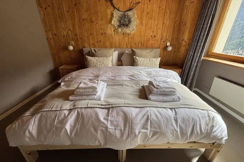 The Zermatt room: a made-up double bed beneath a black-and-white photo, with a view of the valley.
